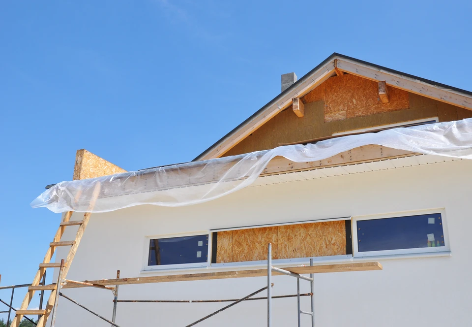 Chantier de construction résidentielle en cours avec ouvriers sur échafaudage travaillant sur façade
