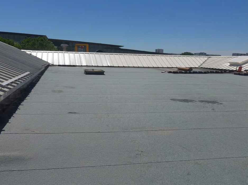 Toiture-terrasse commerciale vue en plongée, revêtement bitumineux minéral gris granulé, avec joints de dilatation visibles